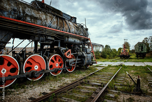 Old steam train locomotive with dramatic cloud background.