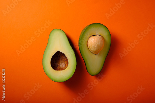 Green avacado on an orange background, top view