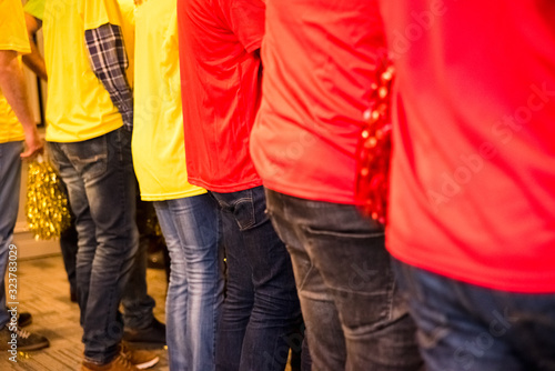 Group of back people with yellow and red colored pom poms.
