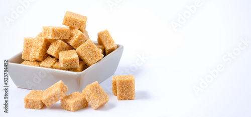 Brown sugar in a square cup on a white background, healthy sugar is used for cooking or desserts.
