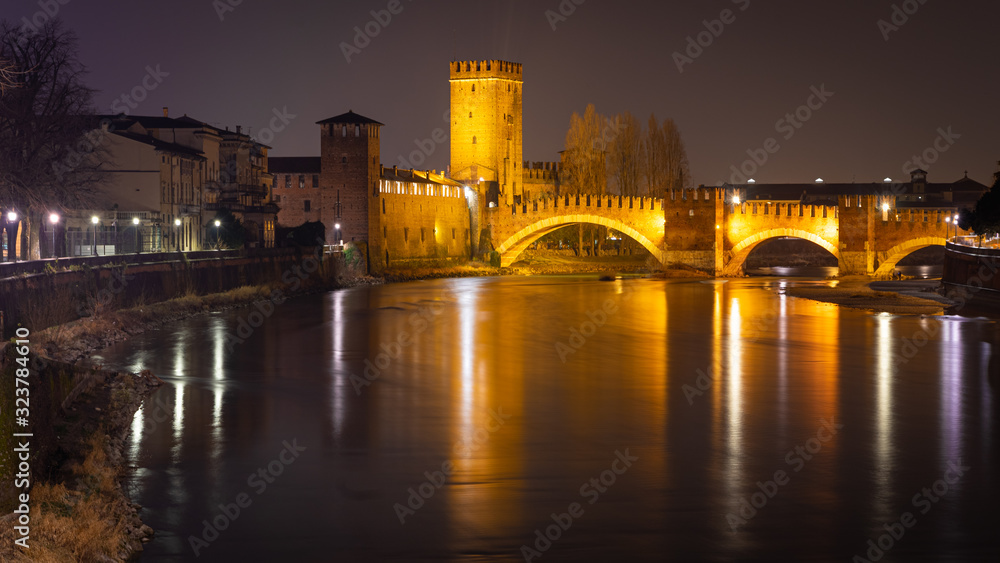 Verona, Italy. Night view of the Adige river which passes under the Scaliger bridge Castelvecchio. The bridge is part of the homonymous fortress Verona, Italy. Night view of the Adige river which passes under the Scaliger bridge Castelvecchio. The bridge is part of the homonymous fortress