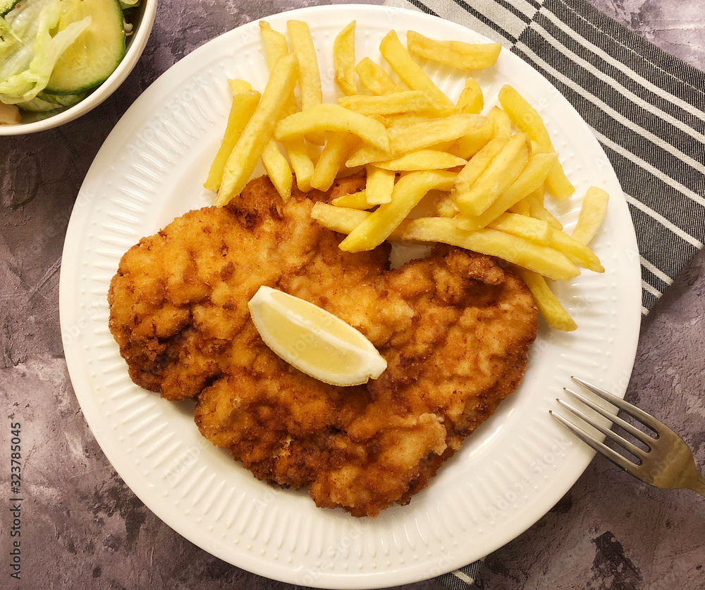 Viennese schnitzel with french fries and lemon. Viennese breaded Escalope. Viennese schnitzel with french fries and lemon. Viennese breaded Escalope.