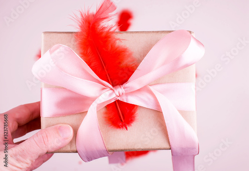 A beautiful festive box with a gift, with bright feathers and hearts. Celebration.