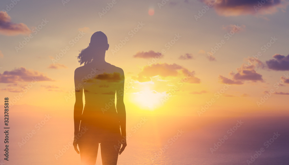 Silhouette of thoughtful woman standing in the sunset. Double exposure 