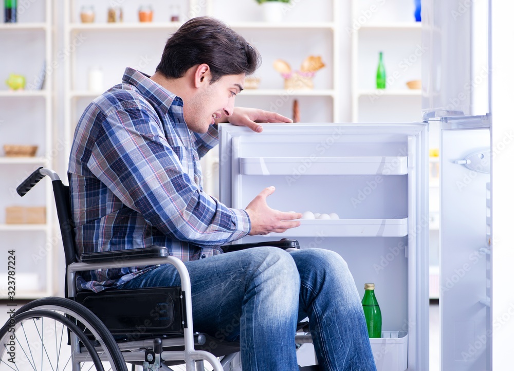 Young disabled injured man opening the fridge door Young disabled injured man opening the fridge door