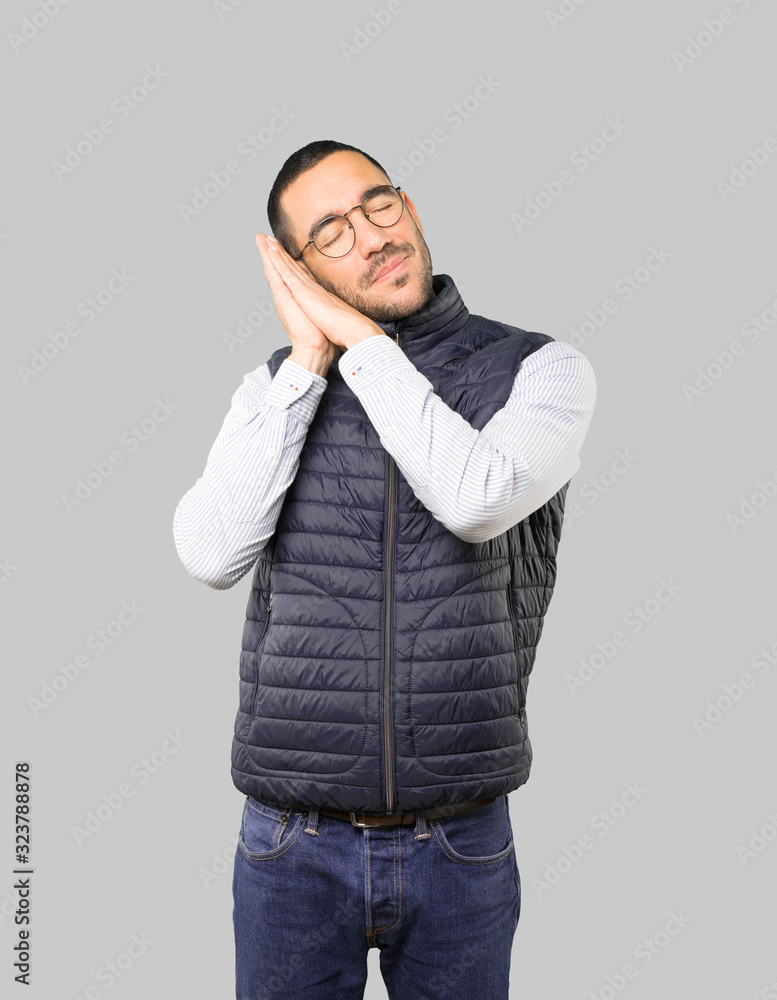 Relaxed young man making a gesture of sleep Relaxed young man making a gesture of sleep
