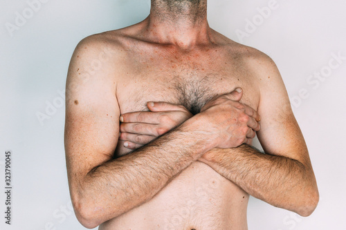 Caucasian man without shirt with hands on chest, isolated on gray background