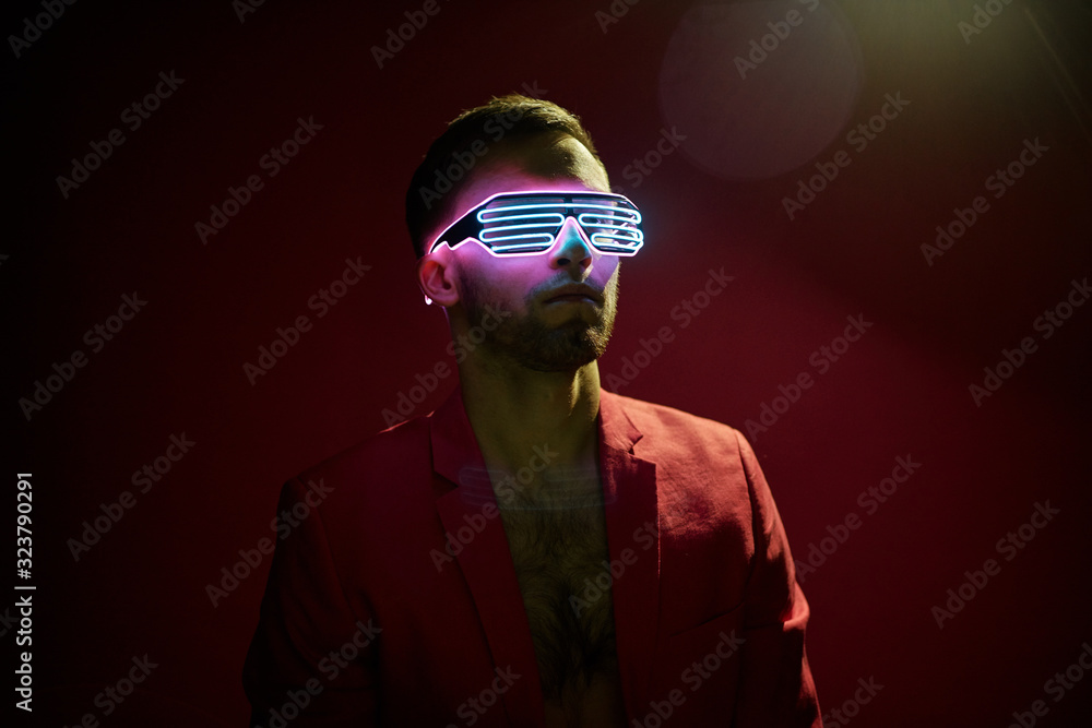 Annoyed young bearded man with closed eyes protecting ears from loud sounds against blue background Annoyed young bearded man with closed eyes protecting ears from loud sounds against blue background