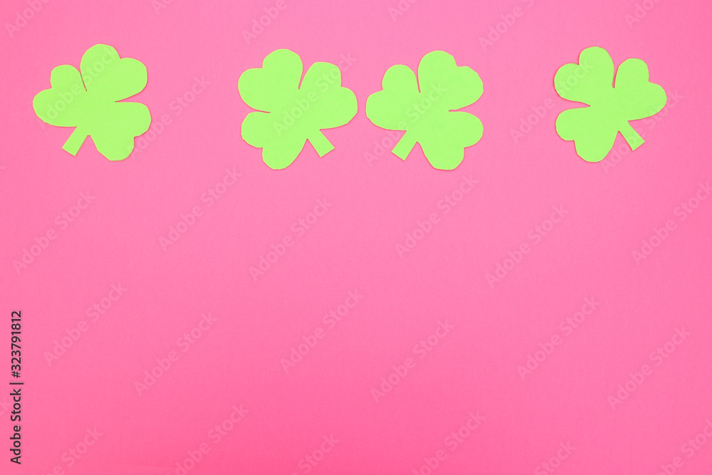 Green hand crafted clovers on colored background 
