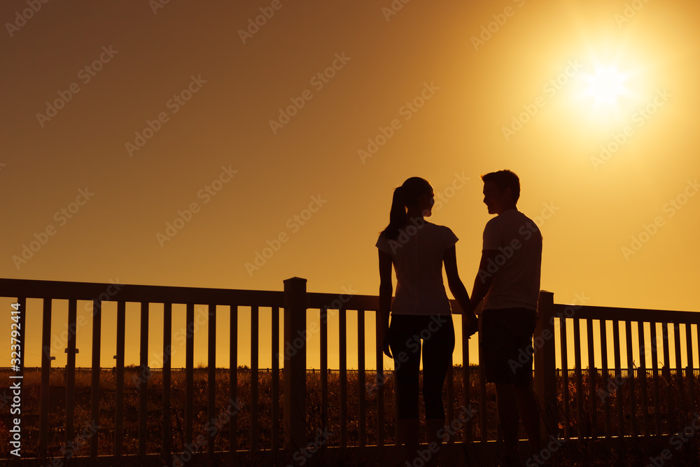 Man and woman standing together outdoors at sunset holding hands. Man and woman standing together outdoors at sunset holding hands.