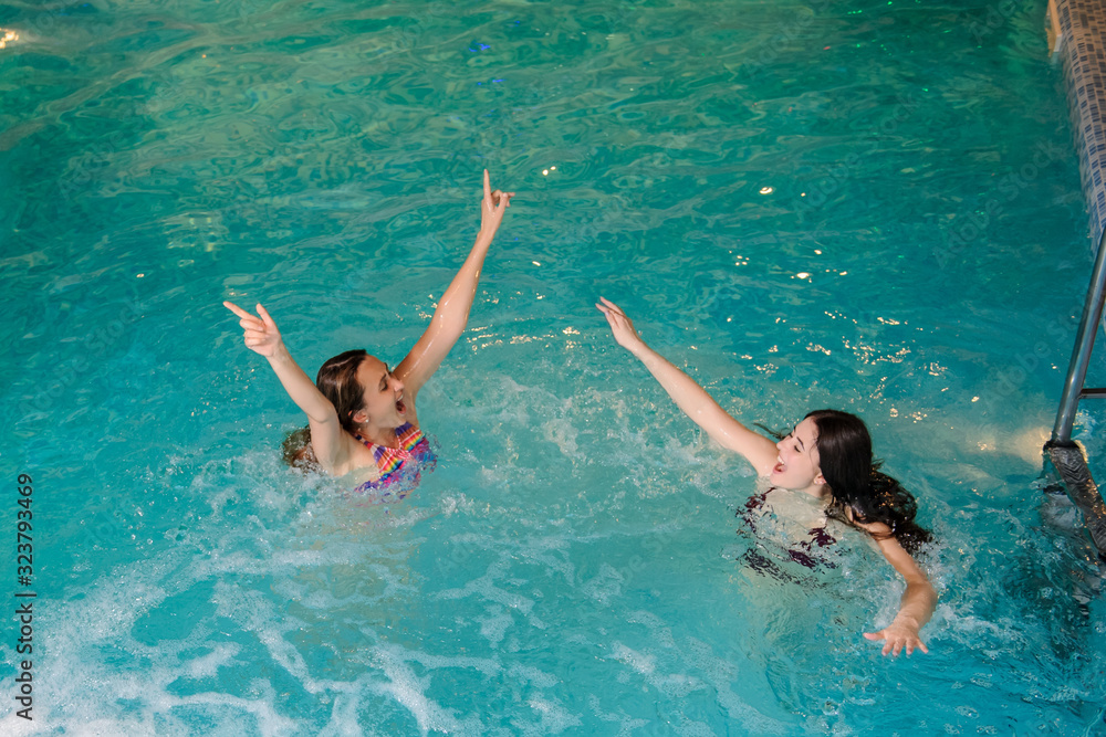 top view of two young women relaxing in the swimming pool of a spa salon