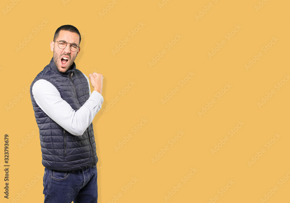 Proud young man doing a gesture of strength with his arm Proud young man doing a gesture of strength with his arm