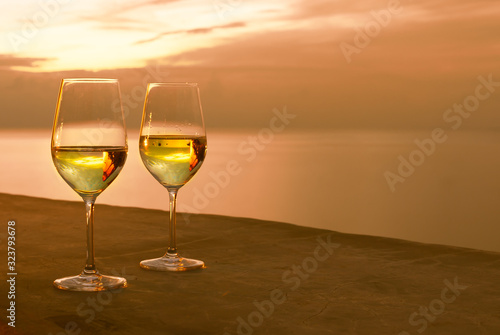 Pair of wine glasses on hotel balcony and beautiful ocean sunset view. 