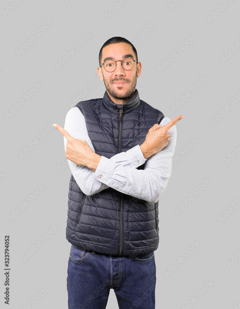 Confused young man poiting in both directions Confused young man poiting in both directions