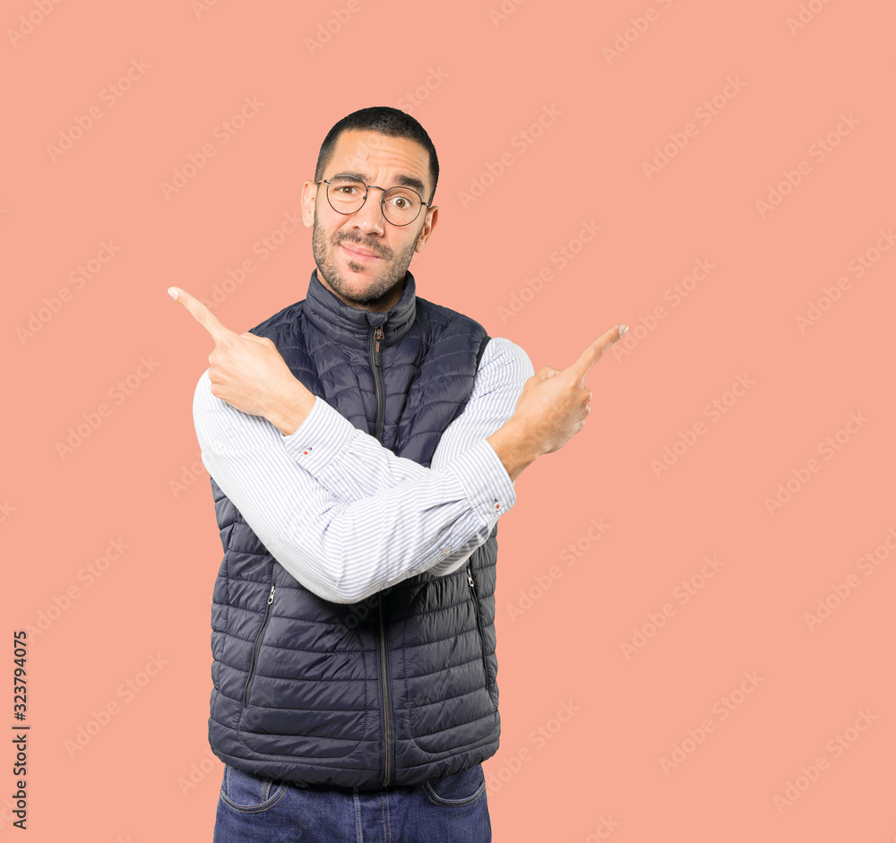 Confused young man poiting in both directions Confused young man poiting in both directions