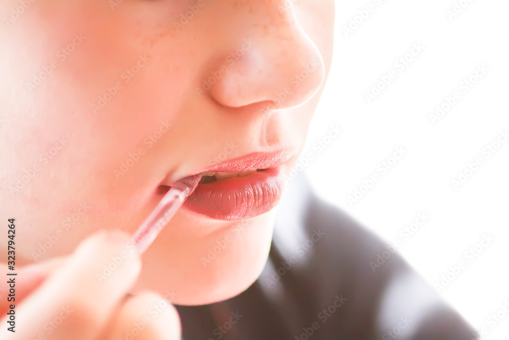 Obraz premium Young attractive teenager girl's face view with makeup. Girl putting lipstick