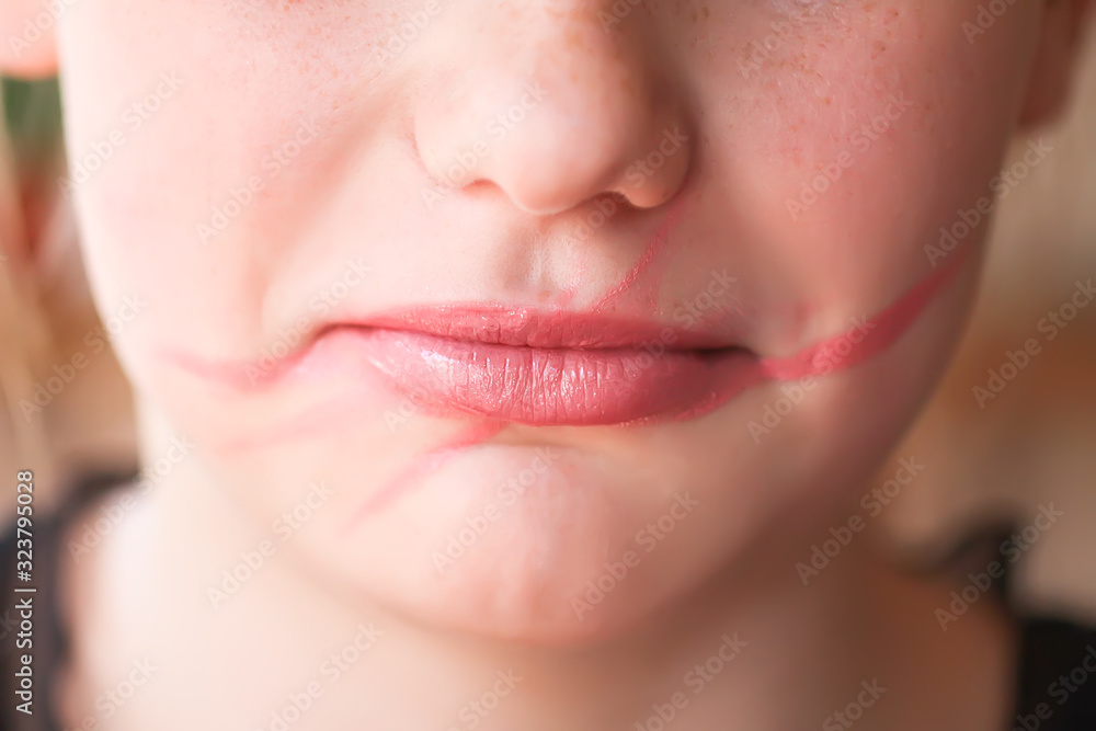 Obraz premium Young attractive teenager girl doing make-up. Lipstick smeared on the lips