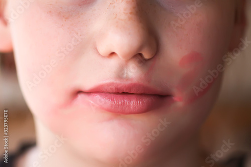 Young attractive teenager girl doing make-up. Lipstick smeared on the lips