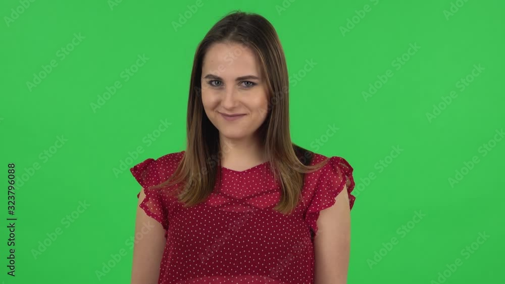 Portrait of tender girl in red dress is coquettishly smiling while looking at camera. Green screen Portrait of tender girl in red dress is coquettishly smiling while looking at camera. Green screen