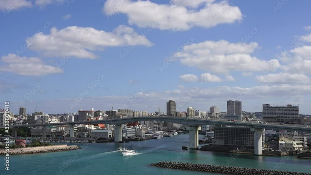 Accelerated video of road and sea traffic in the Japanese city of Naha. Timelapse fast-floating clouds over a beautiful bridge with large road and sea traffic on background of city in Okinawa in 4K Accelerated video of road and sea traffic in the Japanese city of Naha. Timelapse fast-floating clouds over a beautiful bridge with large road and sea traffic on background of city in Okinawa in 4K