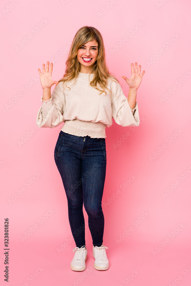 Young blonde caucasian woman standing over a pink background showing number ten with hands. Young blonde caucasian woman standing over a pink background showing number ten with hands.