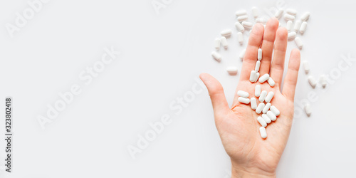 Palm hand full of white scattering pills. Capsules with medicines on light background. Flat lay, top view.