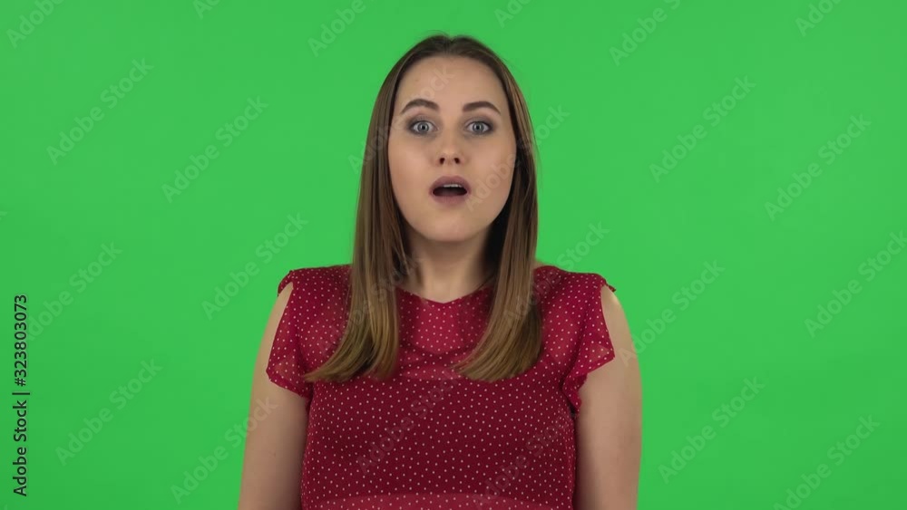 Portrait of tender girl is looking around, covering her mouth with her hand and whispering the secret. Green screen Portrait of tender girl is looking around, covering her mouth with her hand and whispering the secret. Green screen