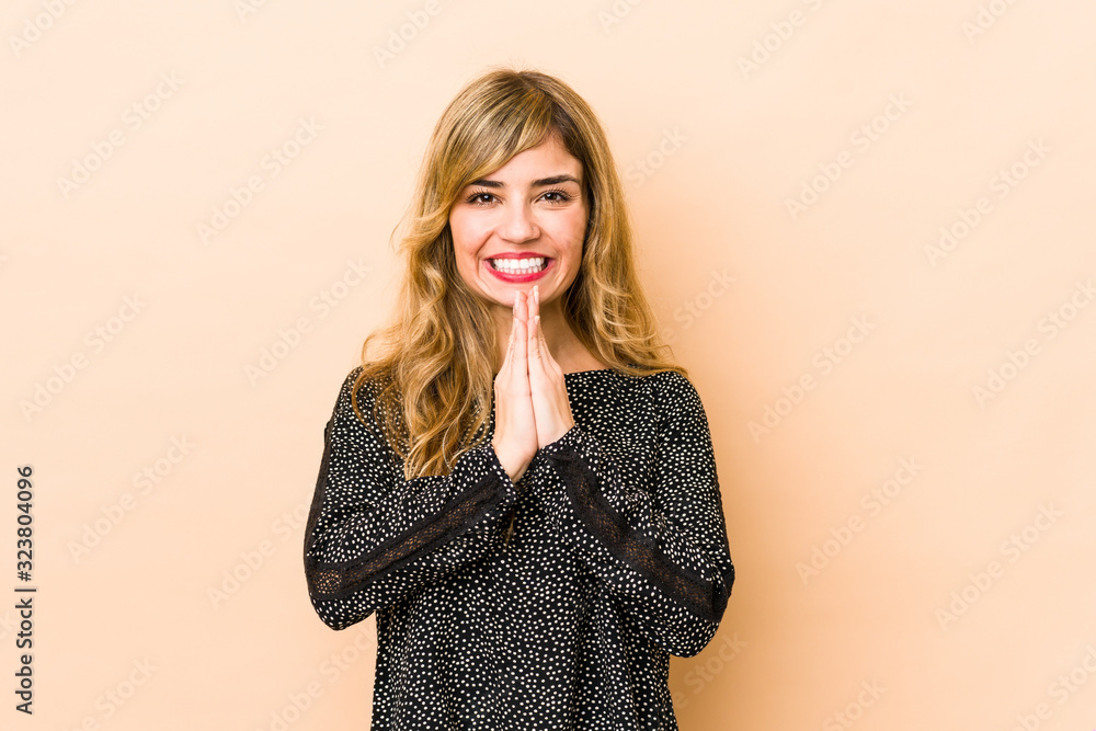 Young blonde caucasian woman holding hands in pray near mouth, feels confident. Young blonde caucasian woman holding hands in pray near mouth, feels confident.