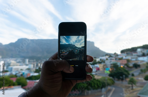 man handholding a smartphone with view of Table Mountain from Bo-Kaap or Malay in background