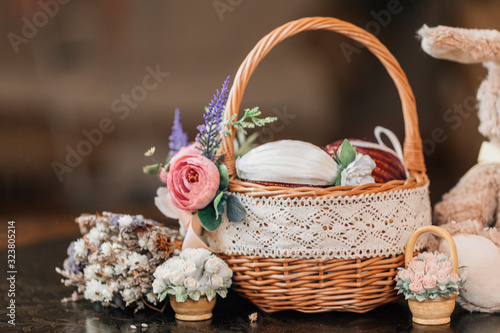 Easter basket with decorated eggs and plush bunny on wooden background.