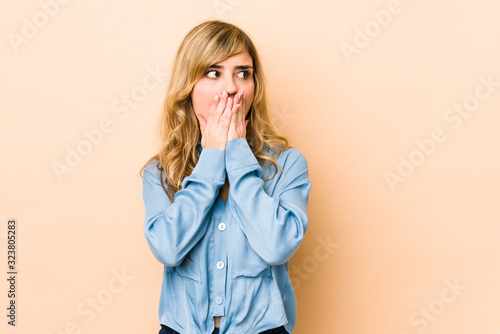 Young blonde caucasian woman thoughtful looking to a copy space covering mouth with hand. © Asier