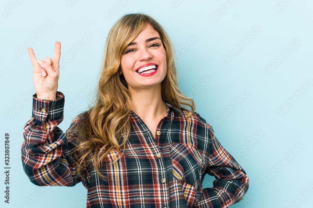 Young blonde caucasian woman showing a horns gesture as a revolution concept. Young blonde caucasian woman showing a horns gesture as a revolution concept.