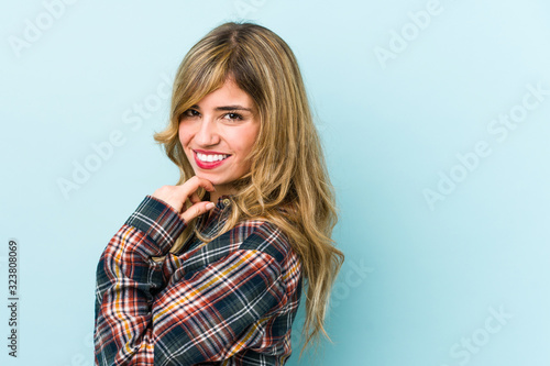 Young blonde caucasian woman smiling happy and confident, touching chin with hand. © Asier