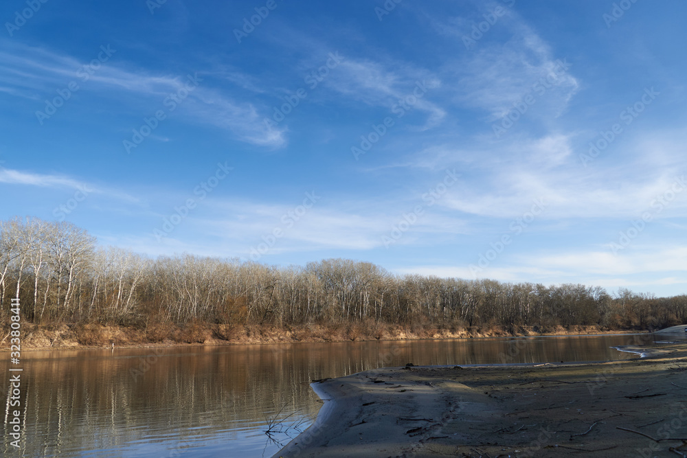 Bright beautiful spring landscape - forest, river and blue sky with soft clouds Bright beautiful spring landscape - forest, river and blue sky with soft clouds