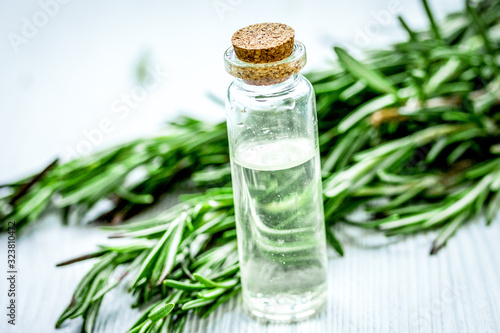 natural cosmetic oil with fresh rosemary on light wooden table background