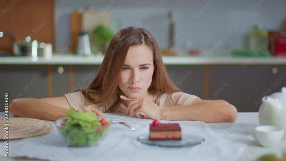 Portrait of smiling woman making decision between salad and cake on kitchen Portrait of smiling woman making decision between salad and cake on kitchen