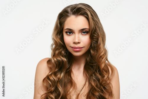 Portrait of young beautiful woman isolated at white background. Blonde girl with long and shiny wavy hair . Smiling friendly girl with curly hairstyle
