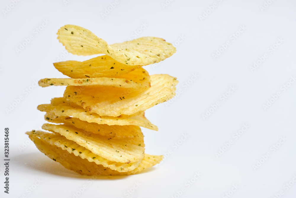 A vertical stack of potato chips with spices on a white background. Copy space. A vertical stack of potato chips with spices on a white background. Copy space.