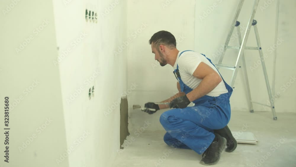 Builder sits and puts mixture on the wall Builder sits and puts mixture on the wall