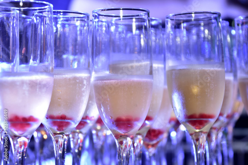 sparkling champagne drinks in crystal glass with blue light for blurred texture background with noise