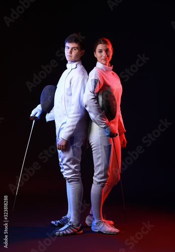 Toned photo of young fencers on dark background