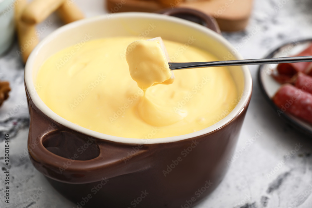 Dipping of crouton into cheese fondue, closeup Dipping of crouton into cheese fondue, closeup