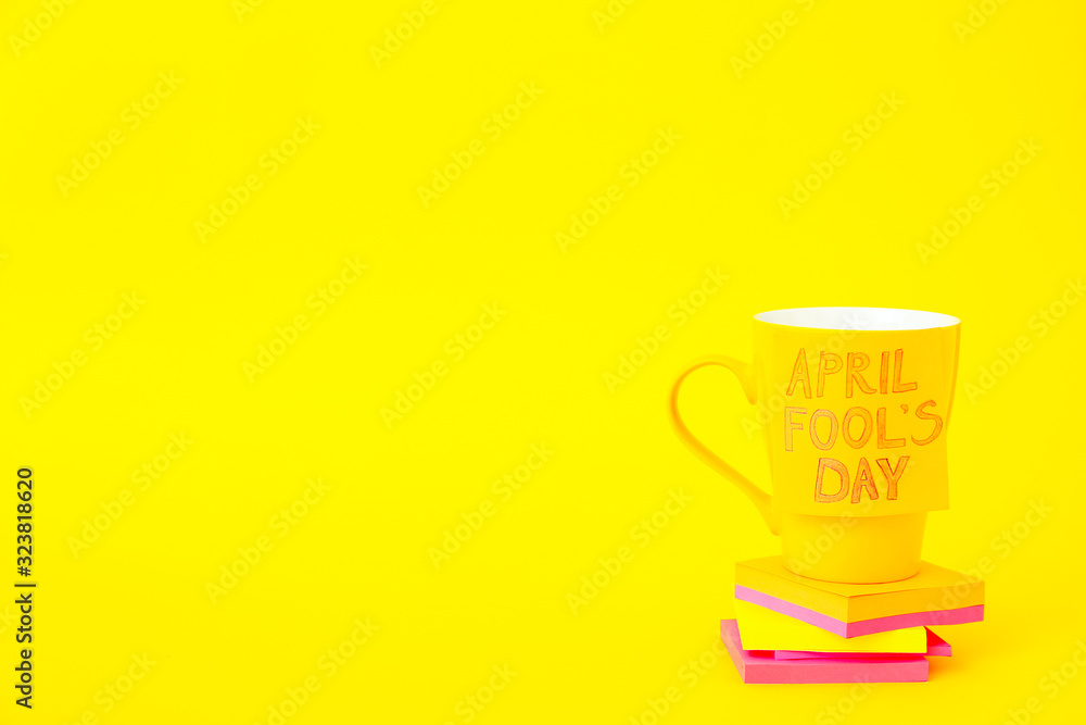 Papers with cup on color background. April Fool's Day prank Papers with cup on color background. April Fool's Day prank