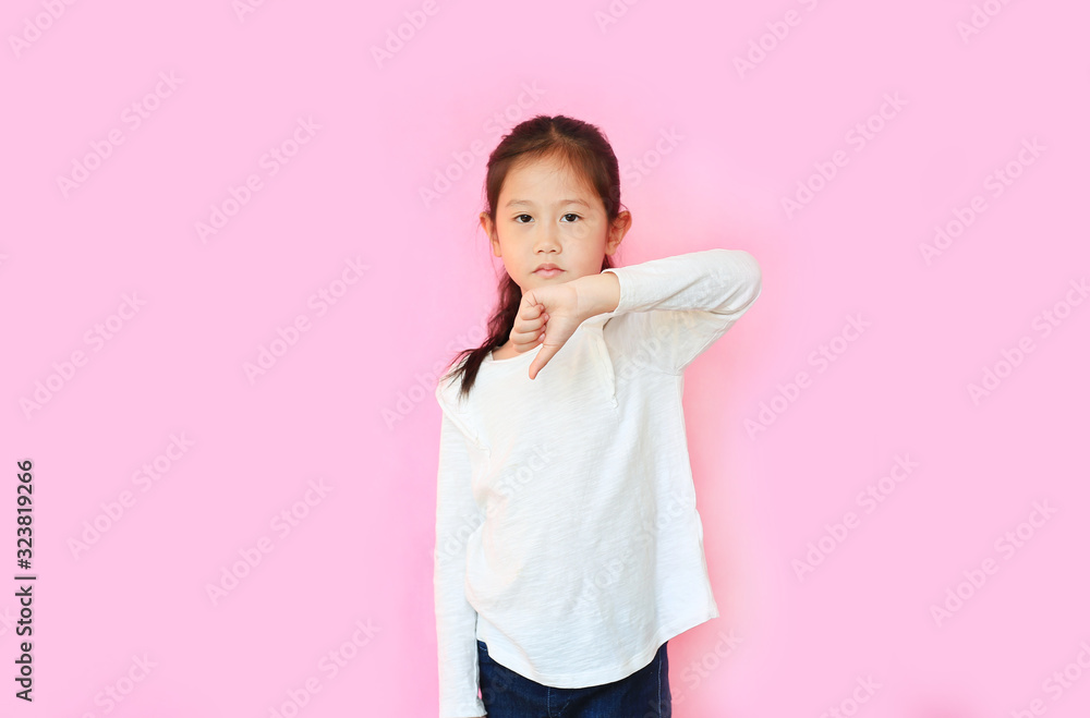 Portrait asian little girl showing dislike gestures with thumb down on pink background. Portrait asian little girl showing dislike gestures with thumb down on pink background.