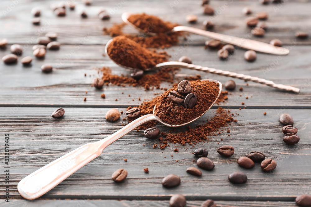 Spoons with coffee beans and powder on wooden background Spoons with coffee beans and powder on wooden background
