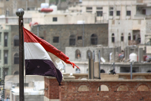 The Yemeni flag appears behind the buildings damaged by the war in the city of Taiz