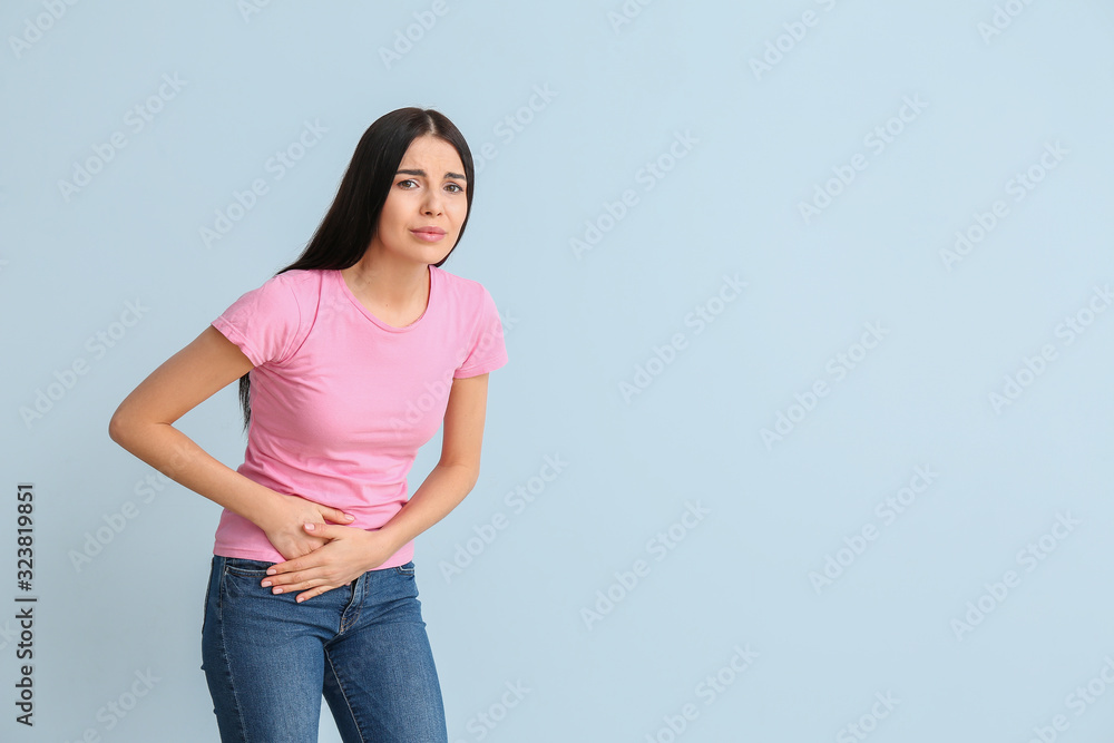 Young woman suffering from menstrual cramps on color background Young woman suffering from menstrual cramps on color background