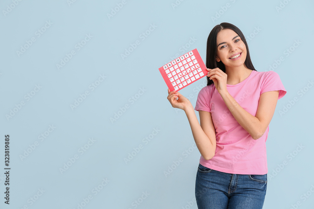 Young woman with menstrual calendar on color background Young woman with menstrual calendar on color background