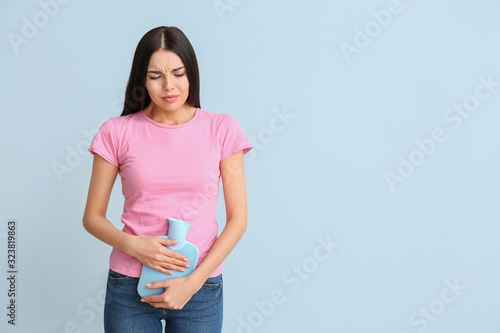 Young woman suffering from menstrual cramps on color background photo