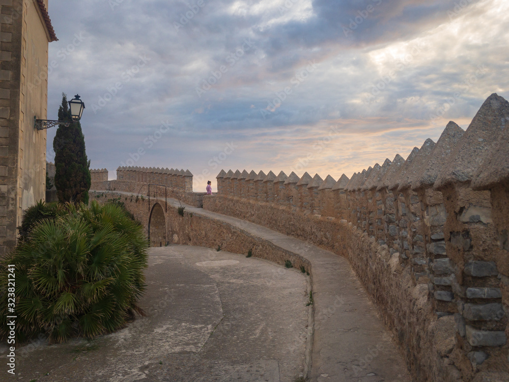 Obraz premium Woman walking along defensive wall of castle Sant Salvador in the city of Arta, Majorca, Spain.